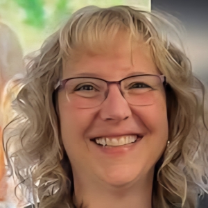Smiling woman with curly blonde hair and purple-framed glasses
