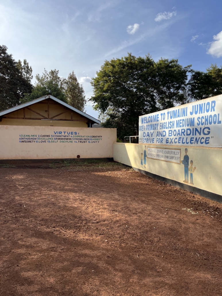 Entrance to Tumaini Junior Pre & Primary English Medium School with painted walls listing virtues and motto Strive for Excellence