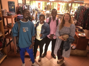 Four smiling people pose together inside a colorful African textile and craft shop